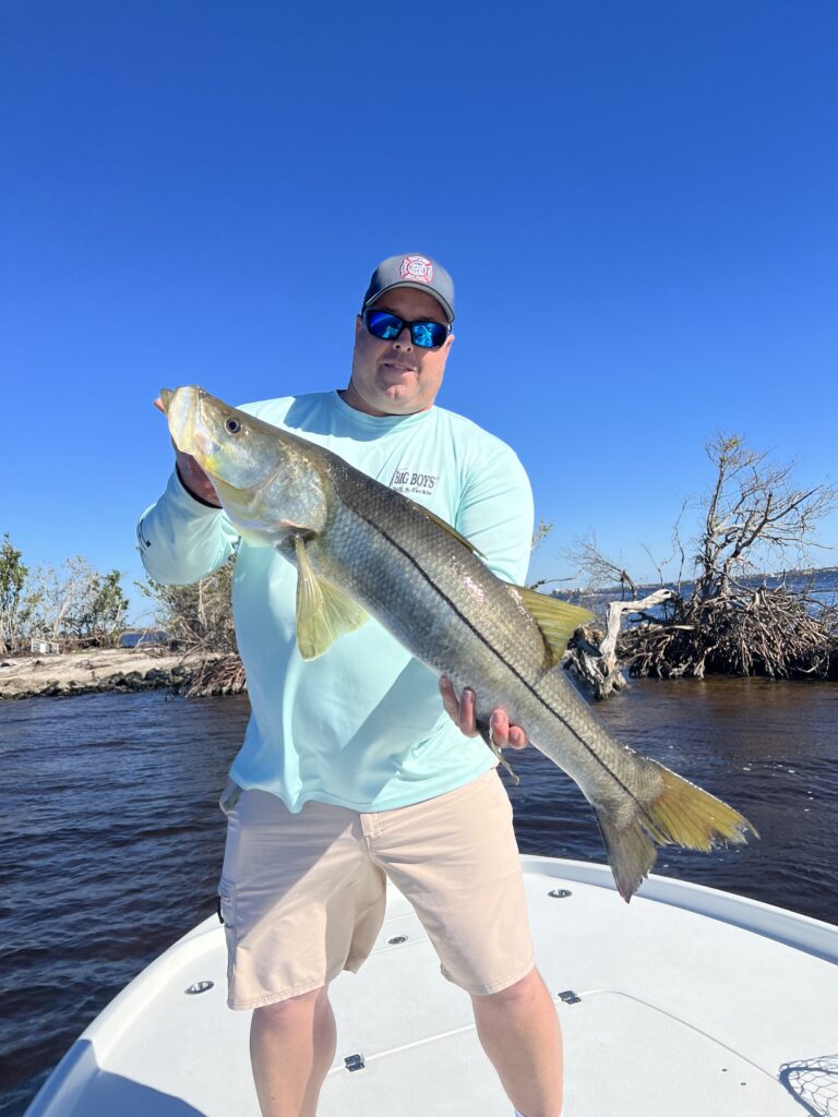 Joshua holding a big snook on his boat in Cape Coral Gulf access canal – local waterfront realtor living the lifestyle